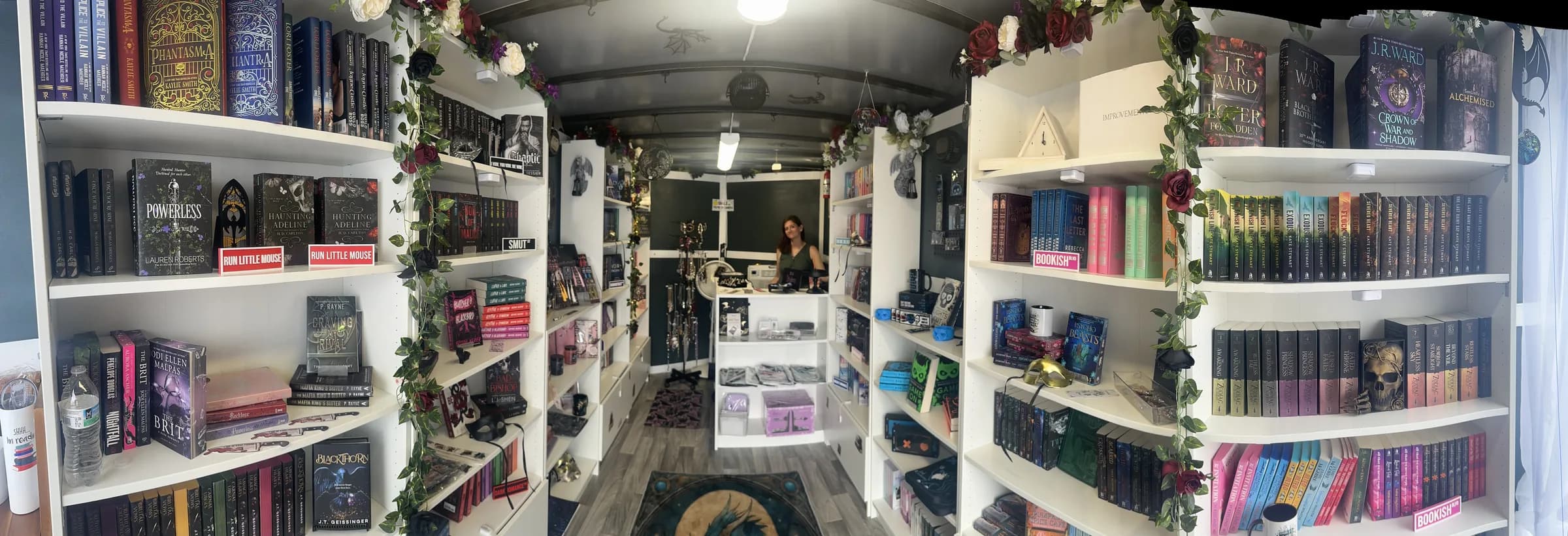 Inside The Well-Loved Shelf mobile bookstore — shelves of romance novels wrapped in greenery